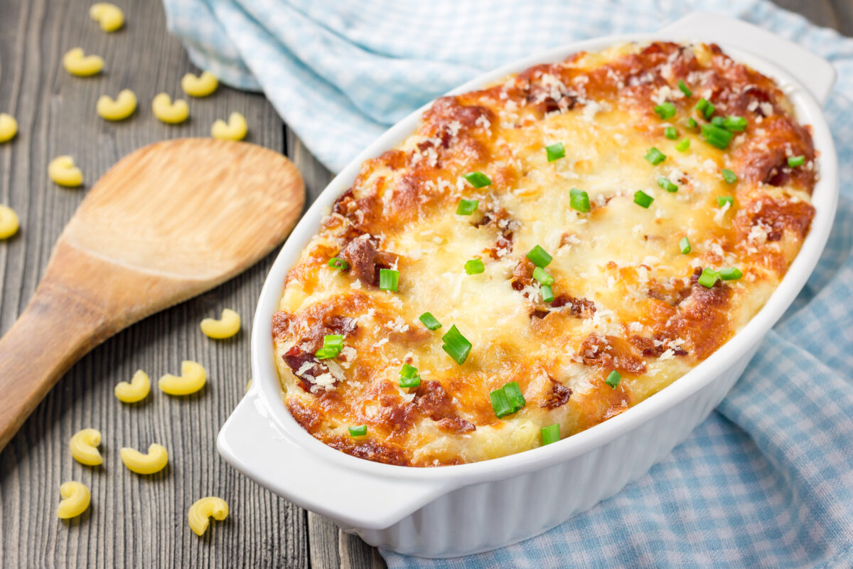 Baked mac and cheese with bacon in a white baking dish lined with gingham linen