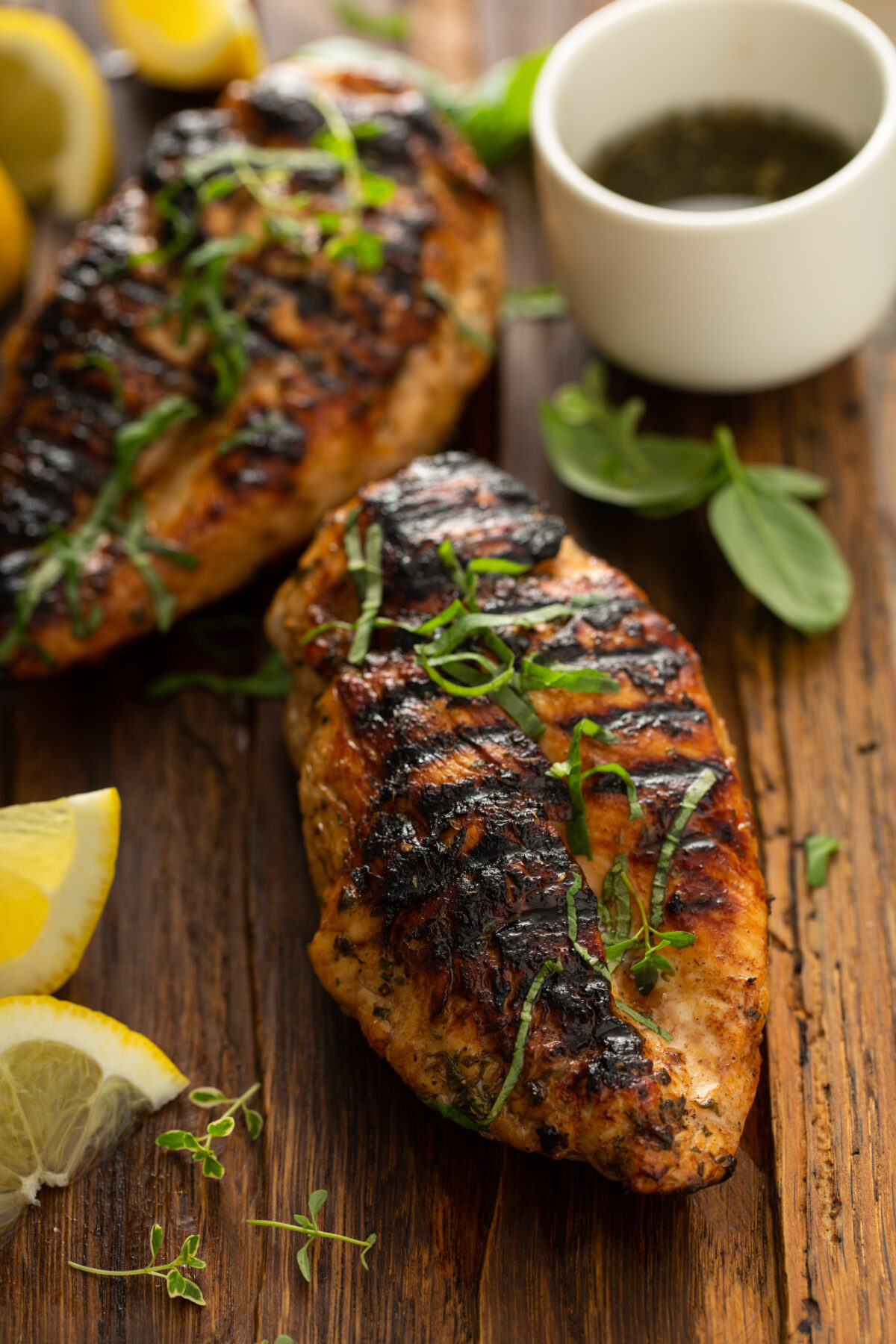 Balsamic grilled chicken breast with fresh herbs on a rustic wooden board