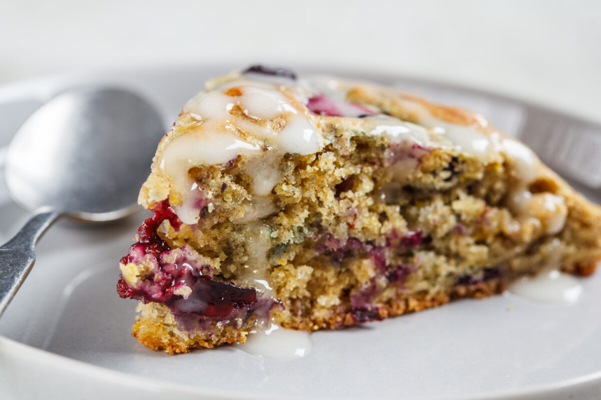 a single blueberry scone, cut into a wedge and placed on a serving plate with an icing drizzle