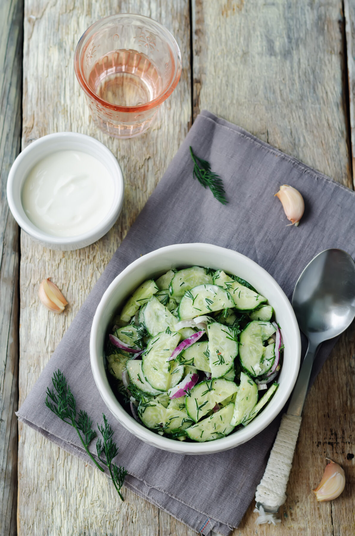 Creamy cucumber salad with red onion, dill and garlic in a serving bowl