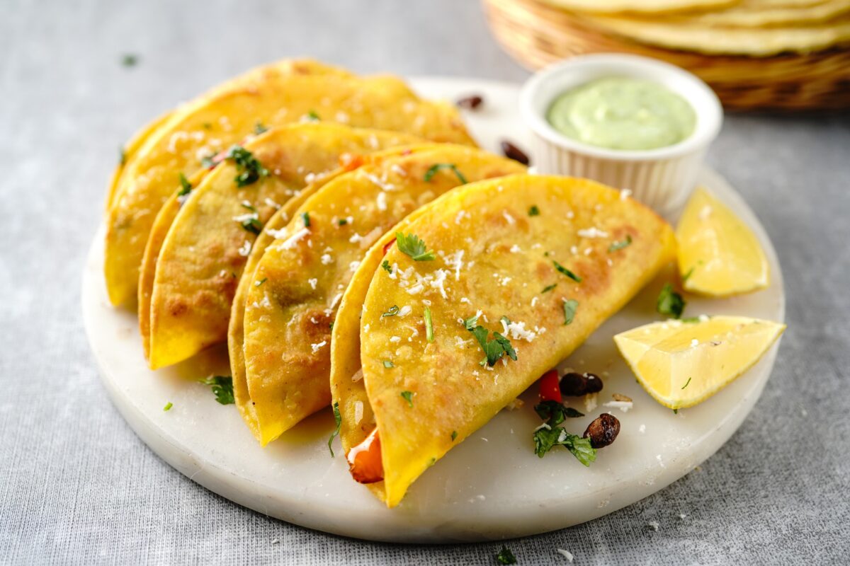 crispy baked black bean tacos on a serving plate with fresh limes