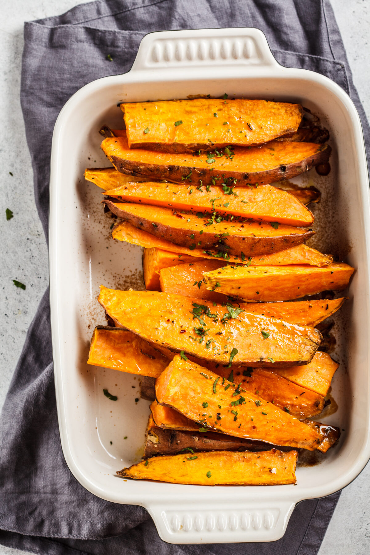 Baked sweet potato slices with spices in oven dish. 