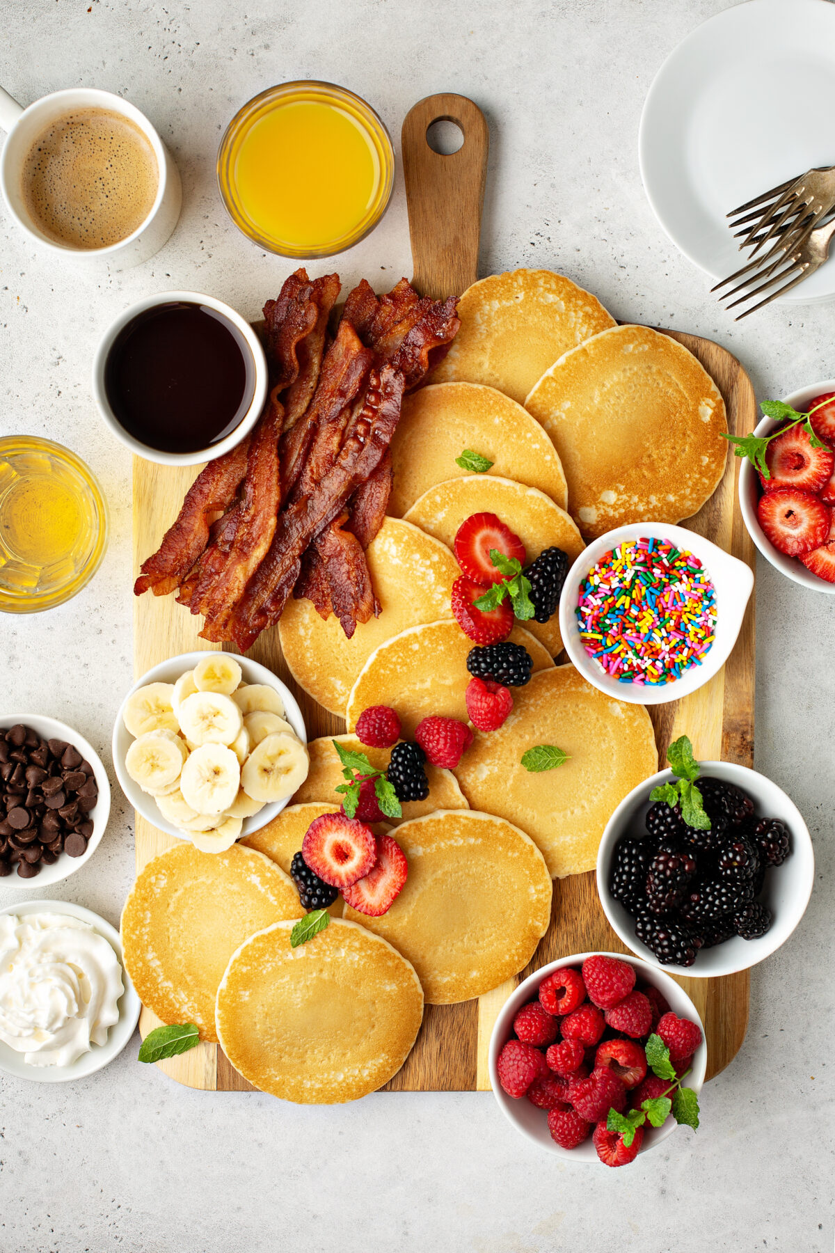 Big pancake breakfast table with berries, bacon and maple syrup