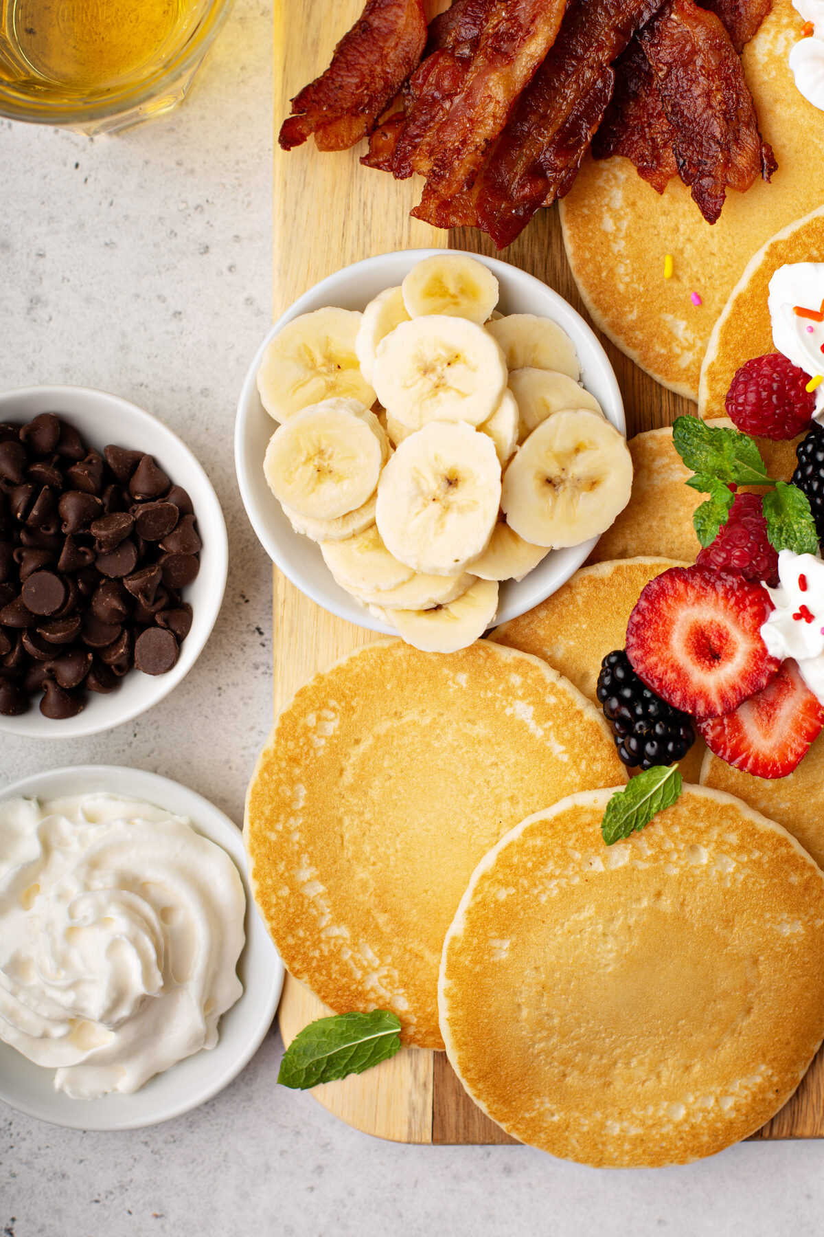 pancakes, fresh fruit, whipped cream and chocolate chips on a serving board