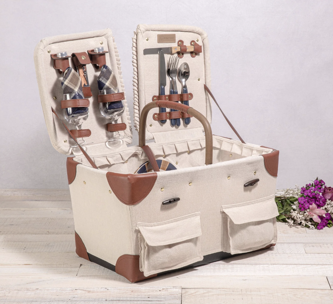 an open picnic basket with wine glasses, linens and silverware
