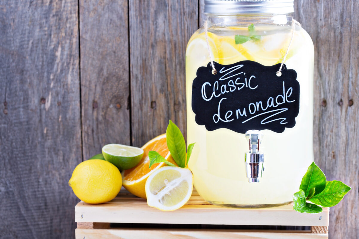 Homemade lemonade in beverage dispenser with fresh lemons