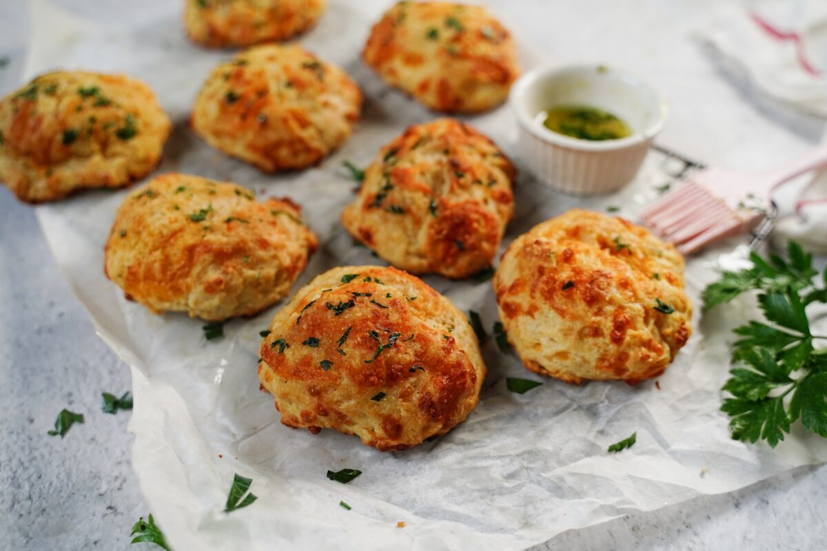 Homemade cheddar biscuits with fresh herbs on parchment paper