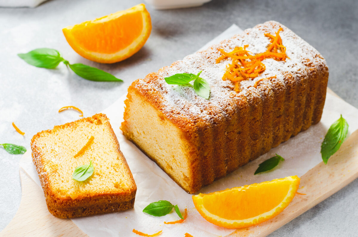 orange pound cake topped with powdered sugar and orange zest