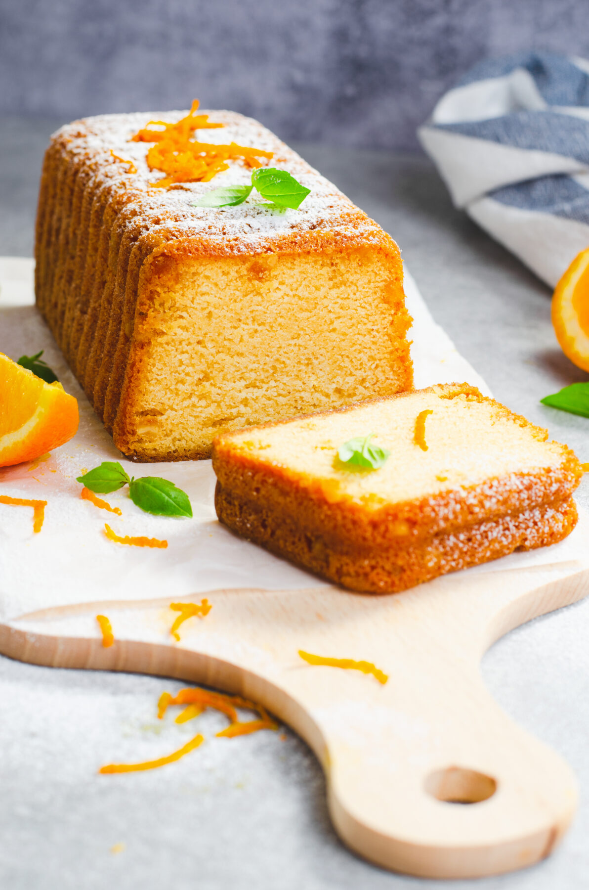 Orange pound cake on wooden board with orange peel and fresh mint