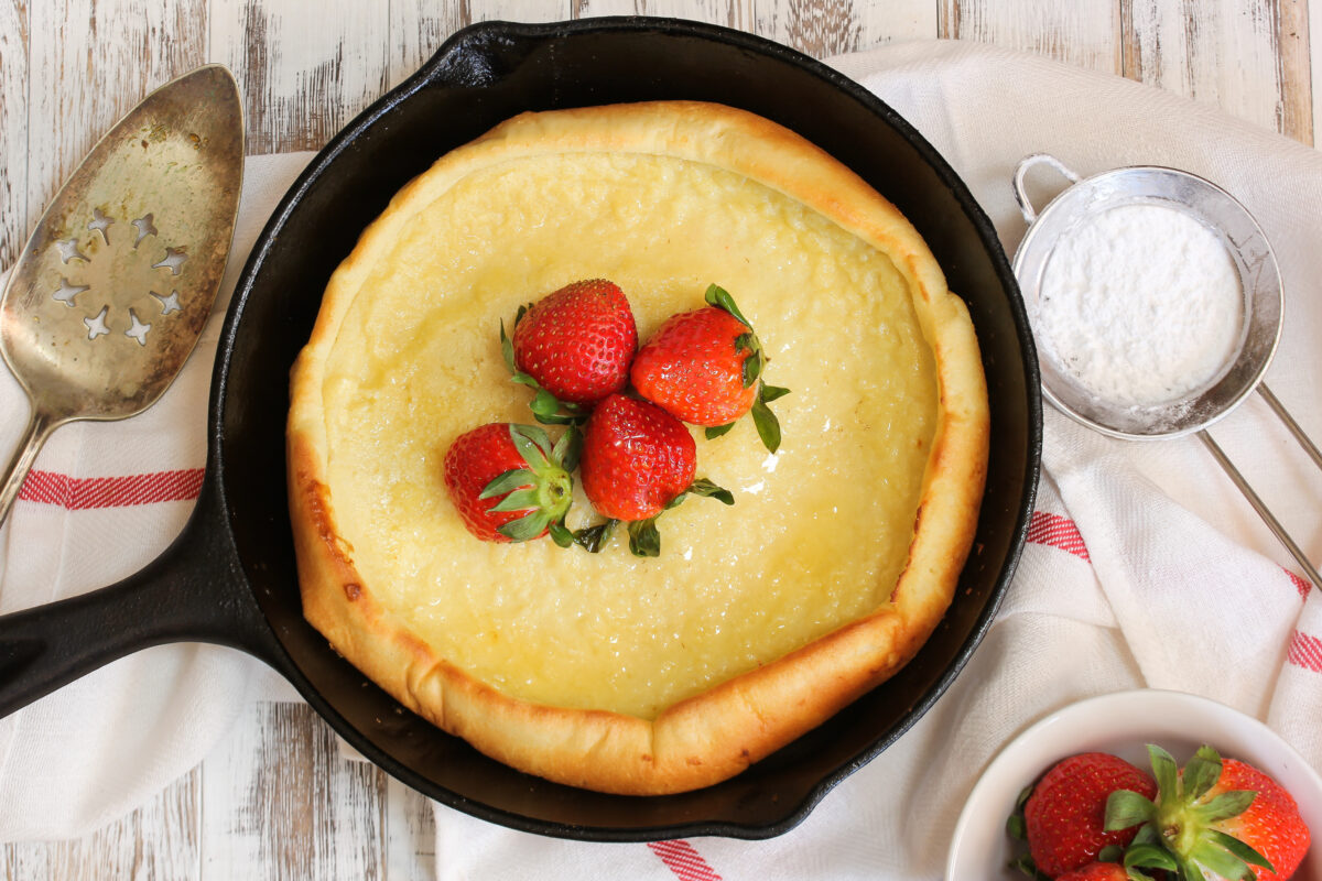 Dutch Baby pancake topped with fresh strawberries baked in cast iron skillet