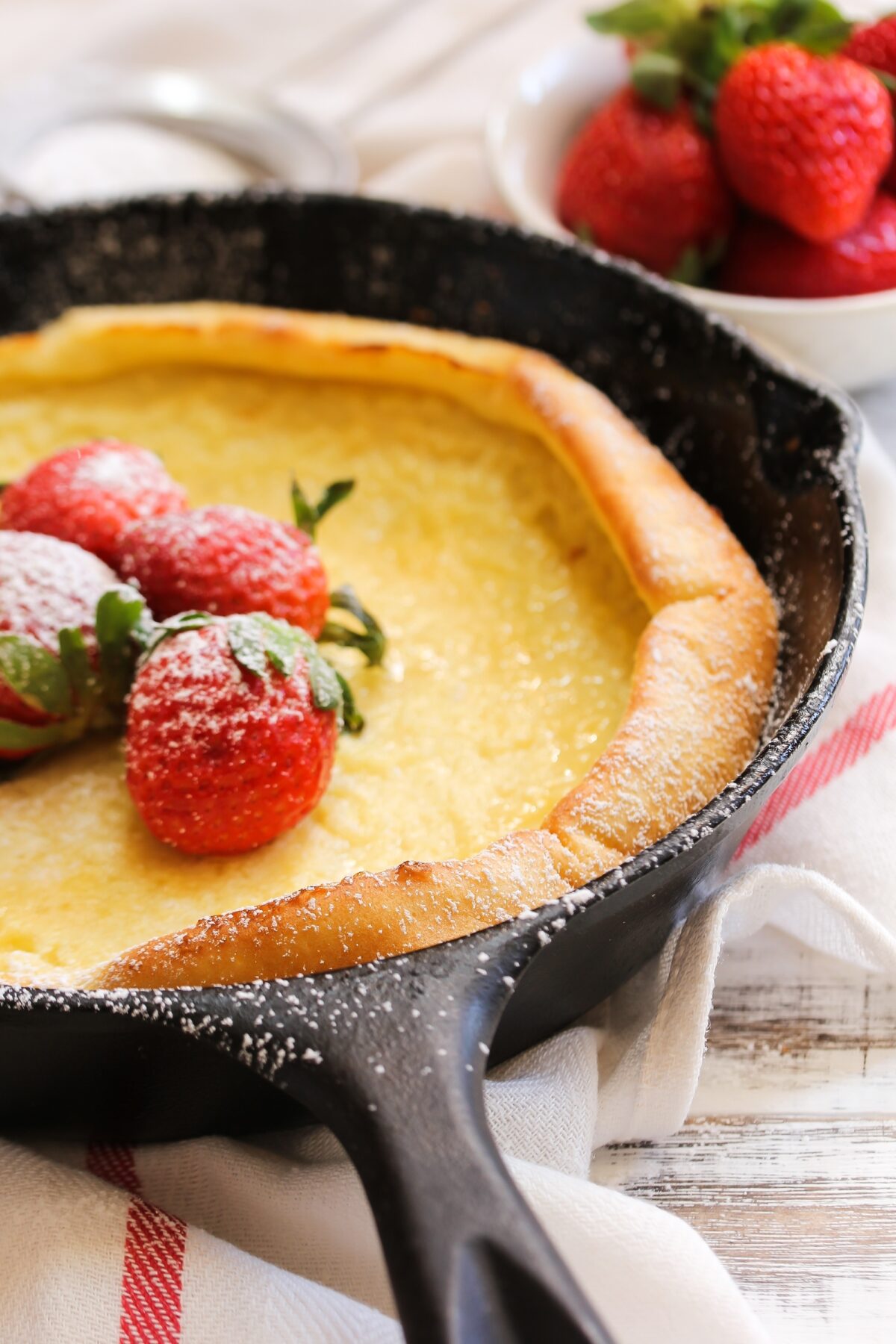 Dutch baby Puffed Pancake baked in cast iron skillet with a striped linen