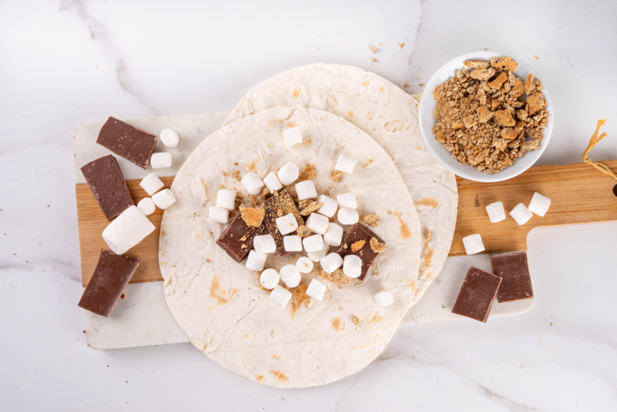chocolate, crushed graham crackers and marshmallows on a tortilla to make smores crunchwraps
