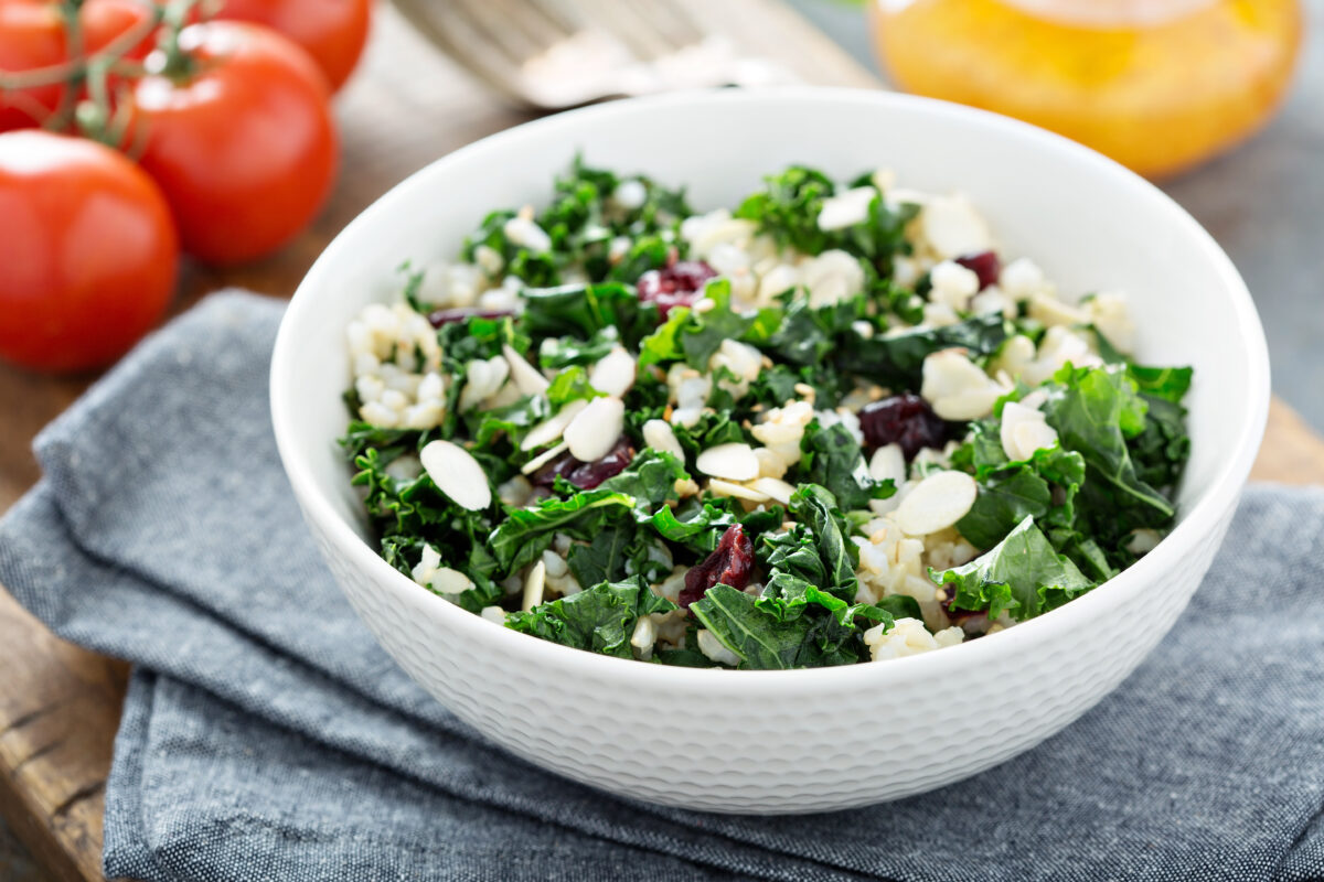 Warm kale salad with brown rice, almonds and dried cranberries on a blue linen