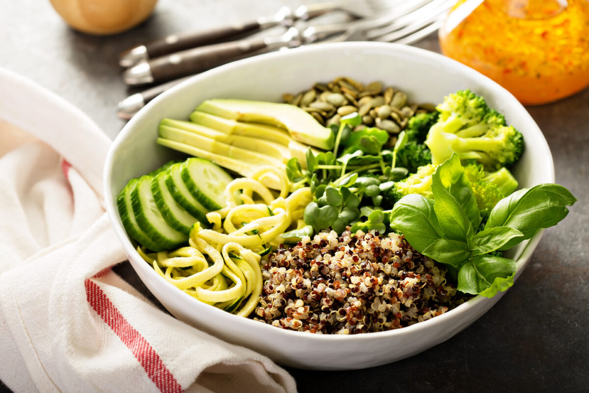 Green, healthy vegan grain bowl with quinoa, avocado, cucumber and zucchini noodles