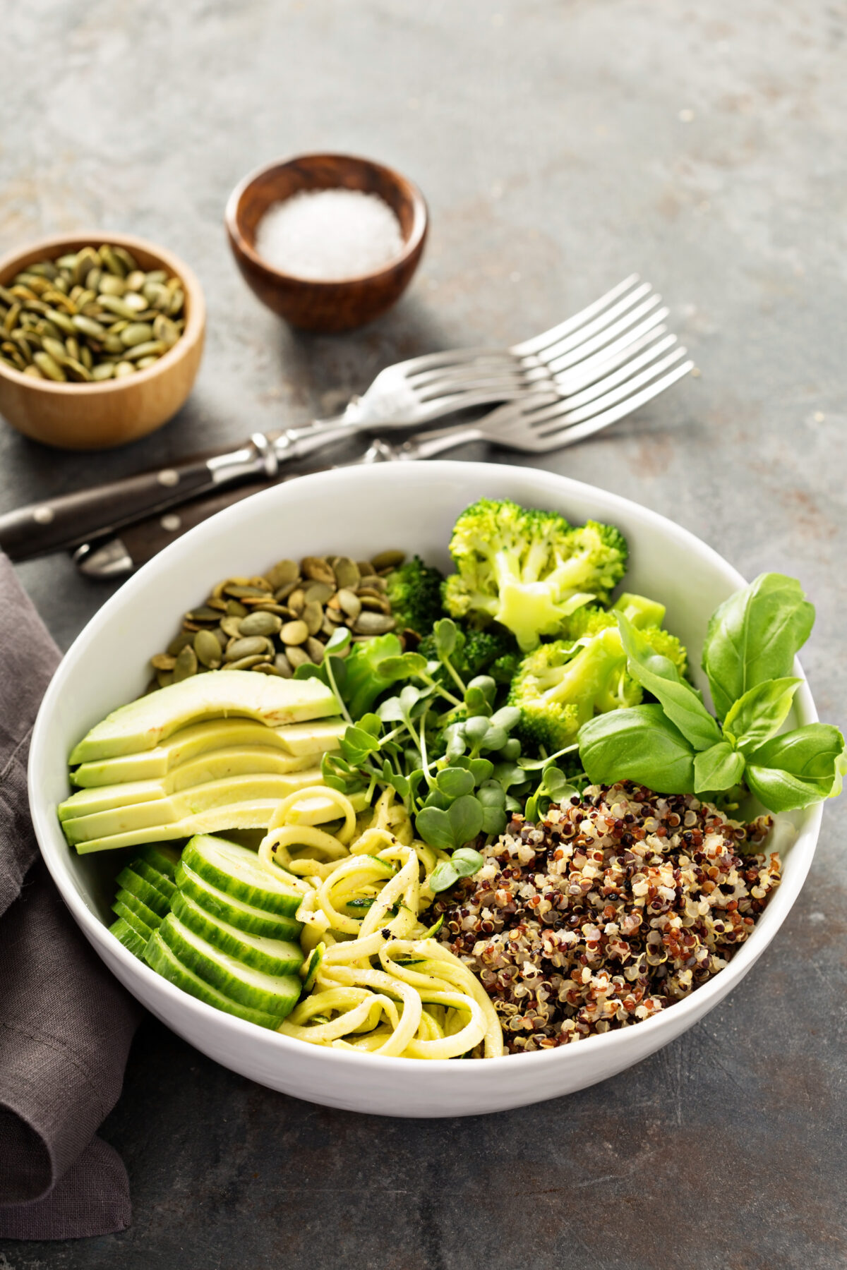 Green, healthy vegan grain bowl with quinoa, avocado, cucumber and zucchini noodles