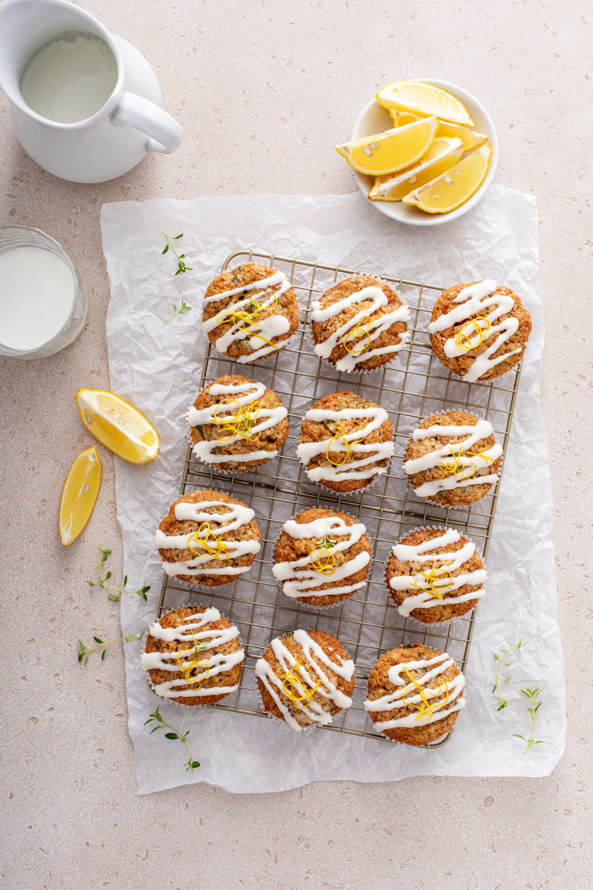 Lemon zucchini muffins with thyme and drizzled with glaze on a cooling rack