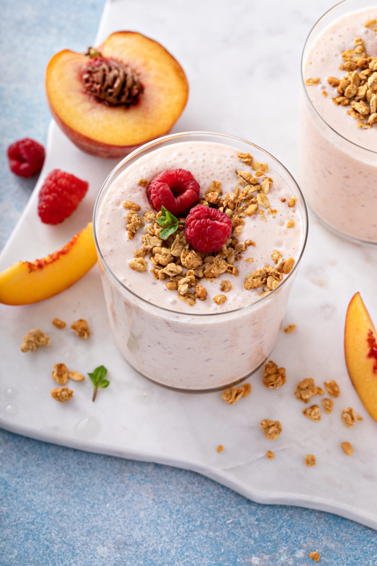 Raspberry peach smoothie topped with granola and berries
