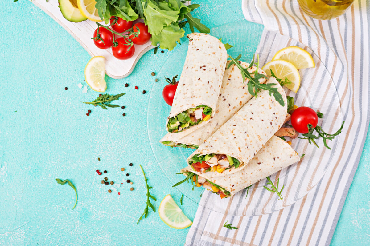 An overhead shot of southwest chicken wraps with fresh veggies on a glass plate