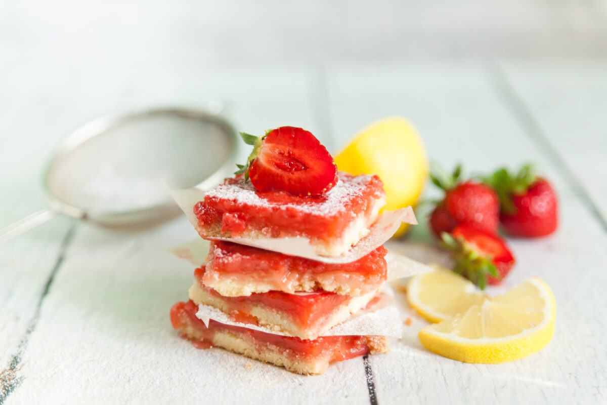 strawberry lemon bars topped with a fresh strawberry and powdered sugar