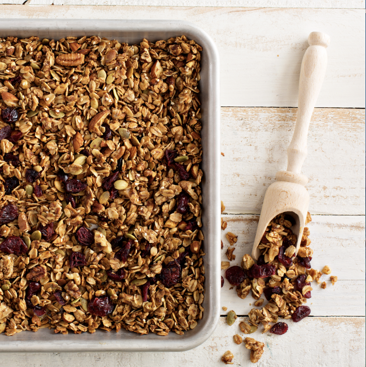 homemade granola with pecans and cranberries on a baking sheet