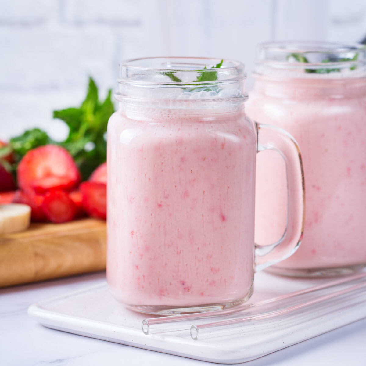 strawberry smoothie in a mason jar glass topped with fresh mint
