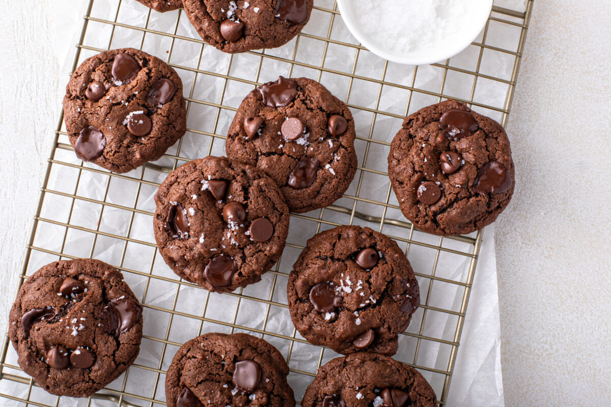 Double chocolate cookies with dark chocolate chips and salt flakes on a cooling rack