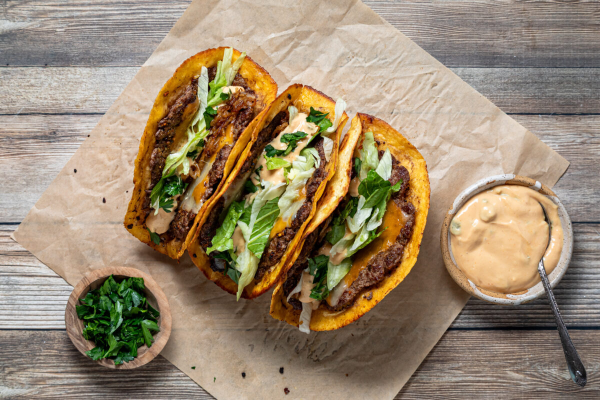 Above view three delicious smash burger tacos with burger sauce and garnished with fresh parsley.