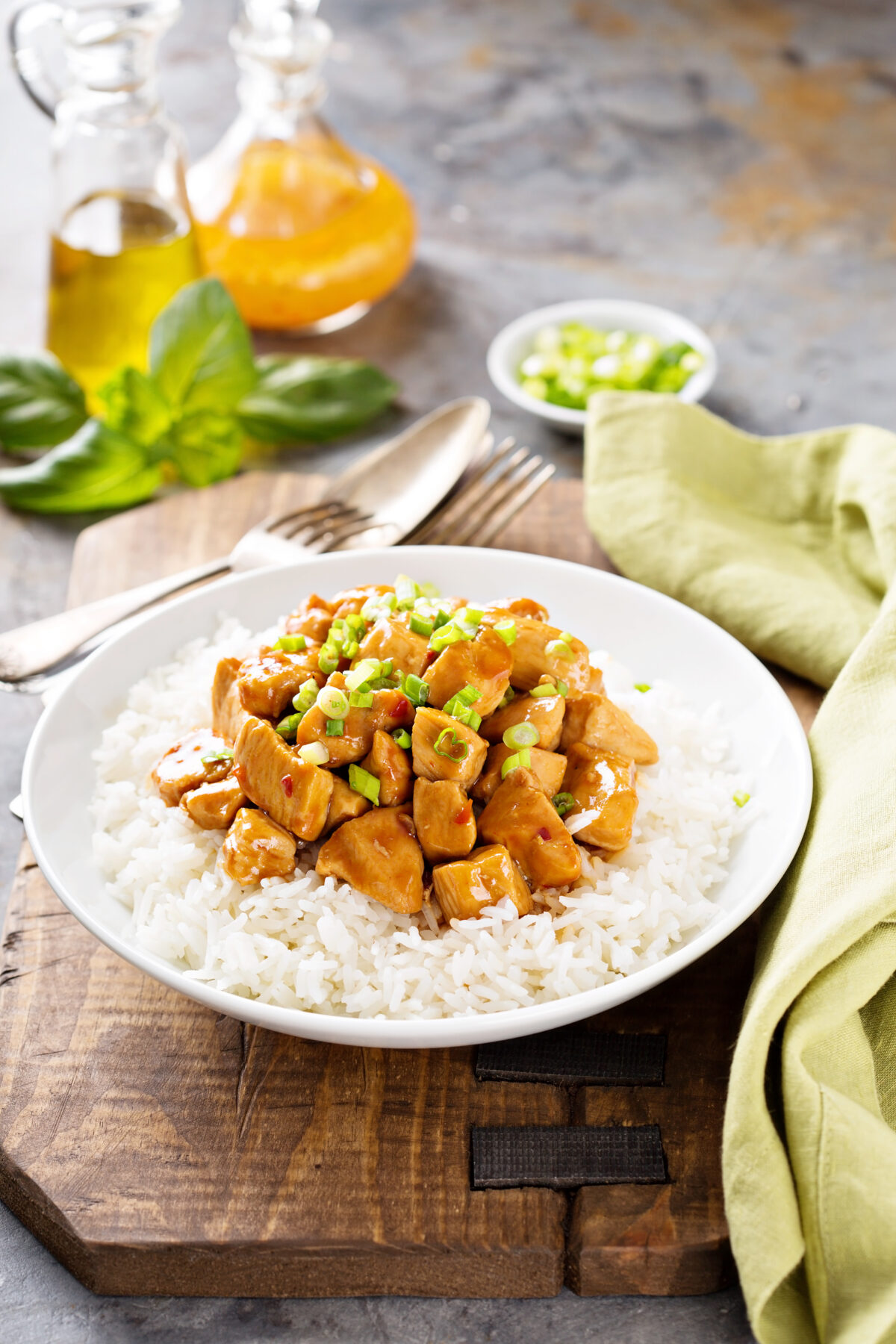 Sweet and sour chicken with rice in white bowl with spring onions