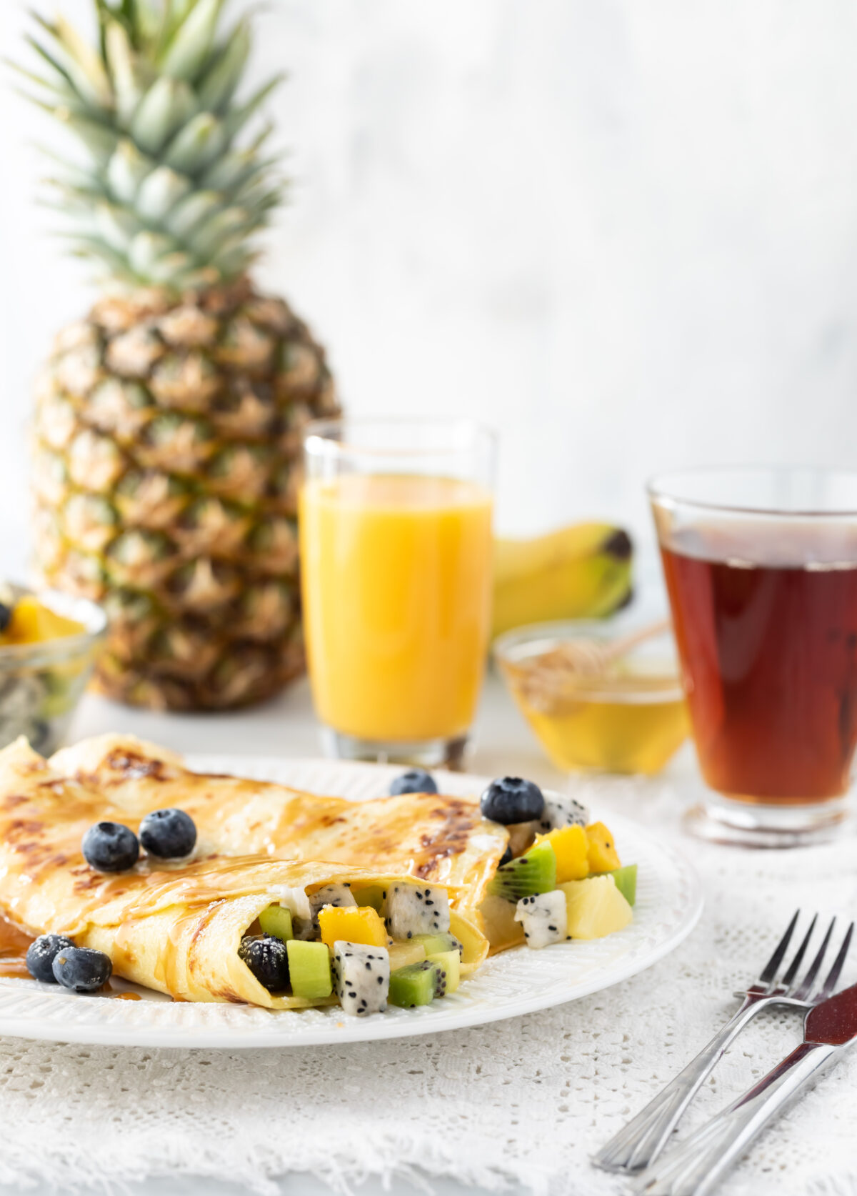crepes stuffed with tropical fruit and drizzled with honey on a serving plate