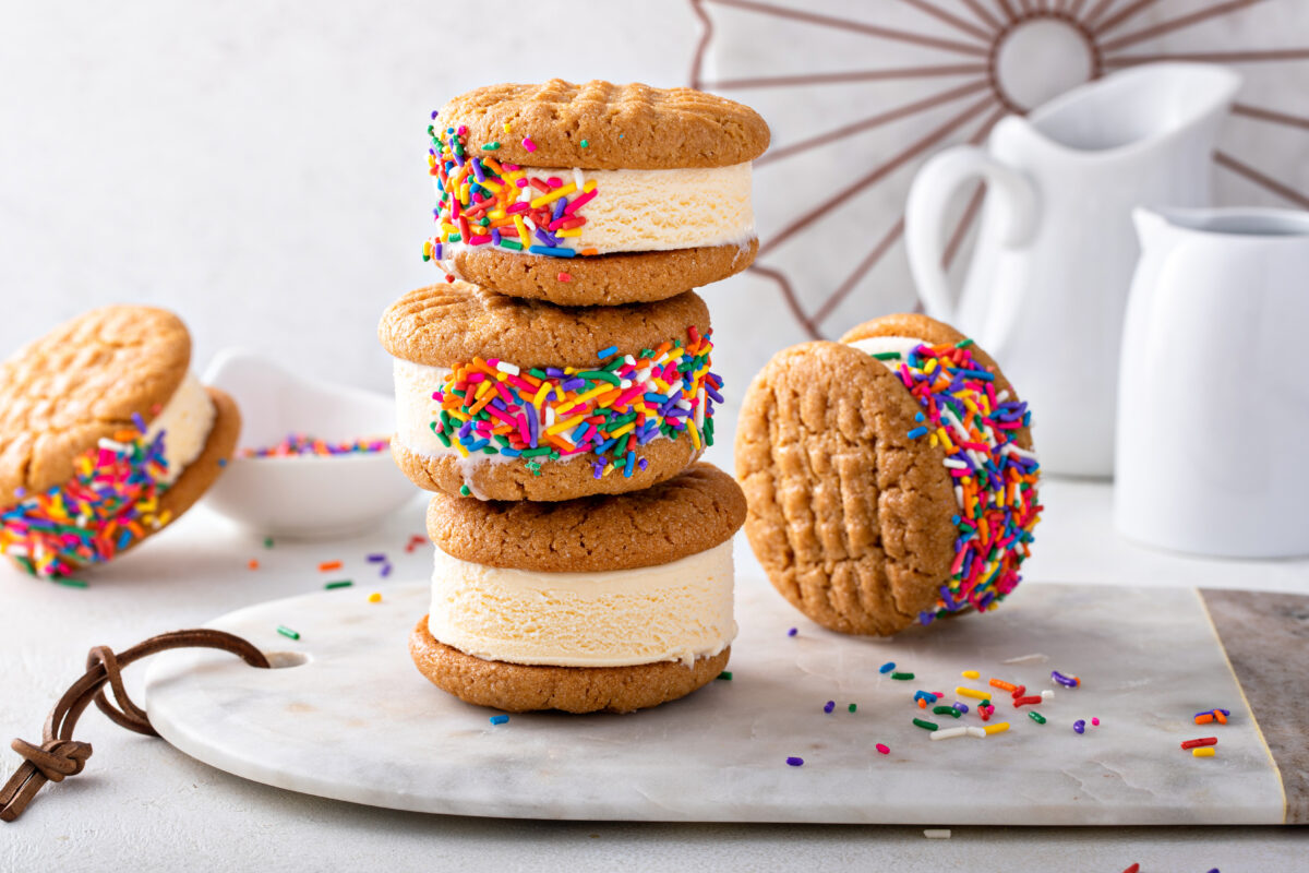 Vanilla ice cream sandwiches with peanut butter cookies with sprinkles piled on the table