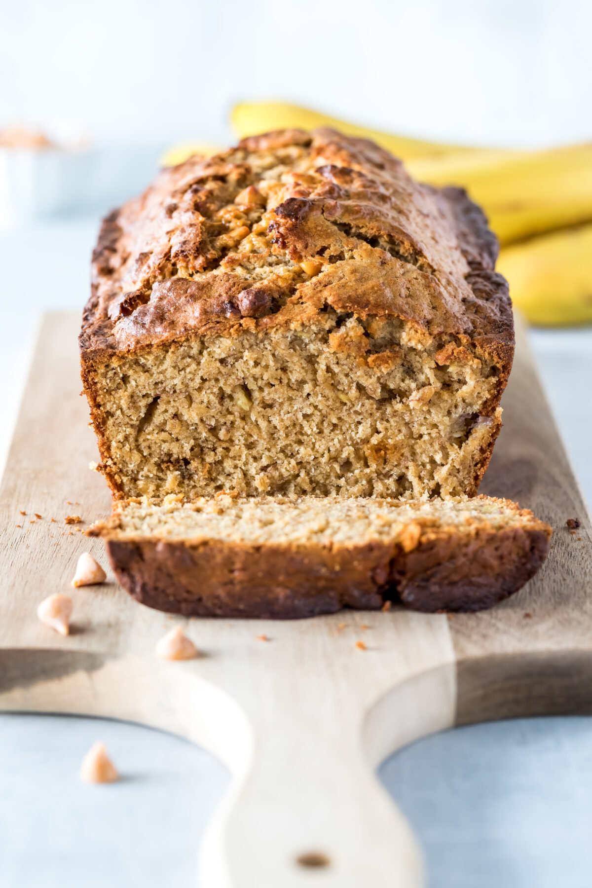 Straight on vertical view of a banana bread loaf that is sliced into with one slice in front.