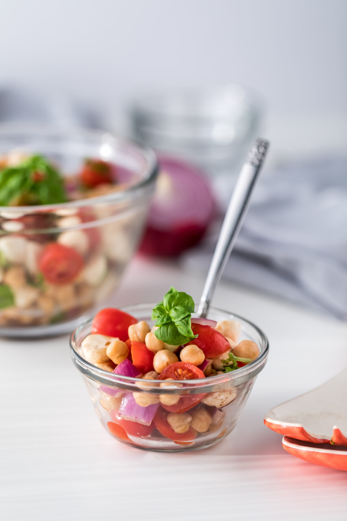 chickpea caprese salad in a small glass bowl with fresh basil