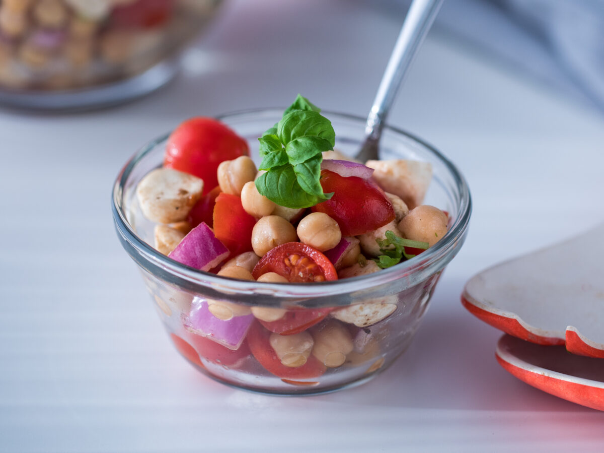 chickpea caprese salad in a small bowl with fresh basil