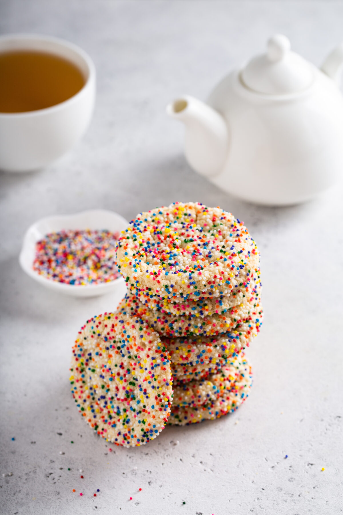 Sugar cookies with sprinkles and a bottle of milk on white background