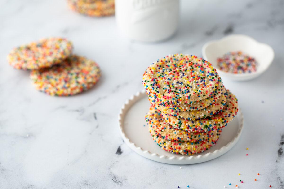 Sugar cookies with sprinkles and a bottle of milk on white background