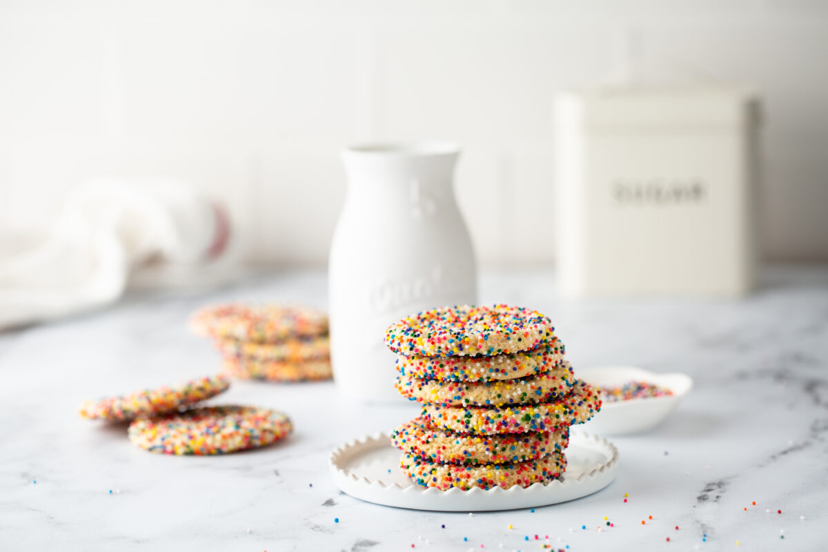 Sugar cookies with sprinkles and a bottle of milk on white background