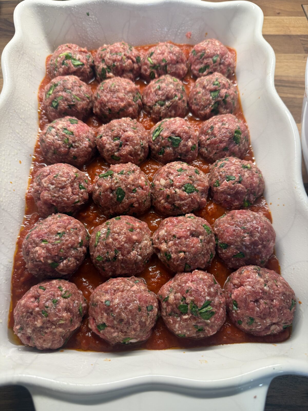 high protein meatballs with spinach in a baking dish with tomato sauce