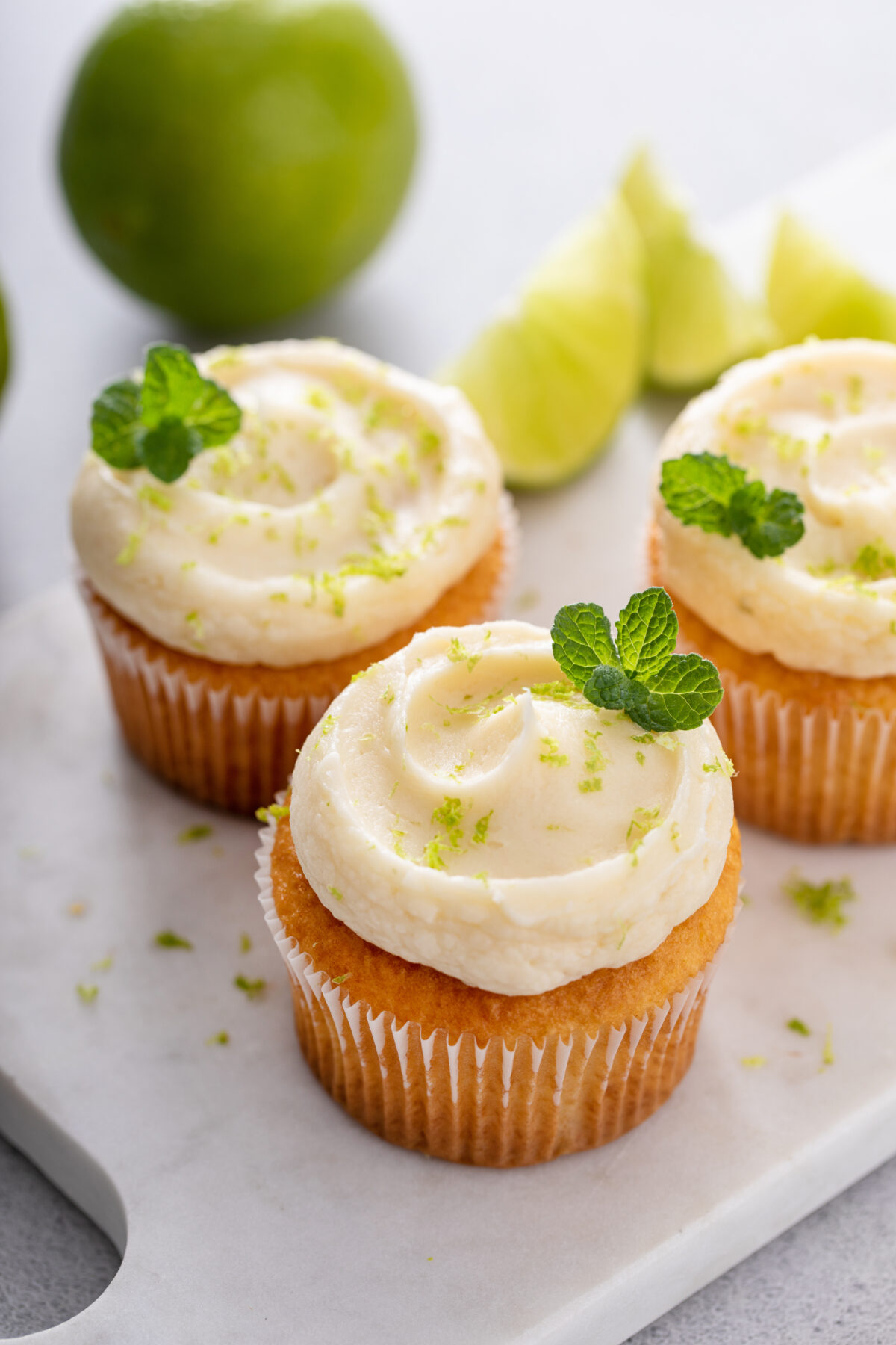 homemade coconut lime cupcakes with lime and coconut garnished with mint leaf