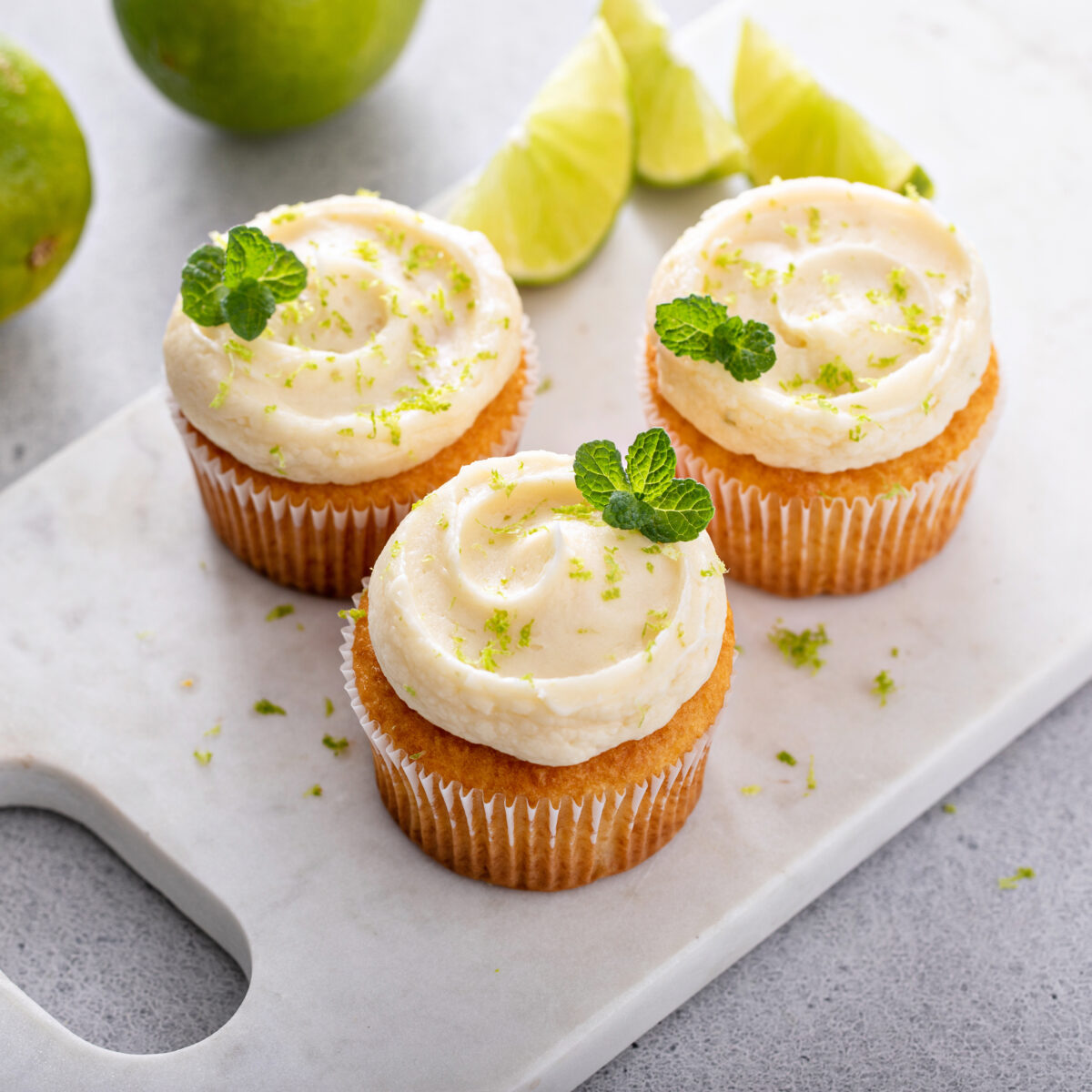 homemade coconut lime cupcakes on a serving plate garnished with fresh mint