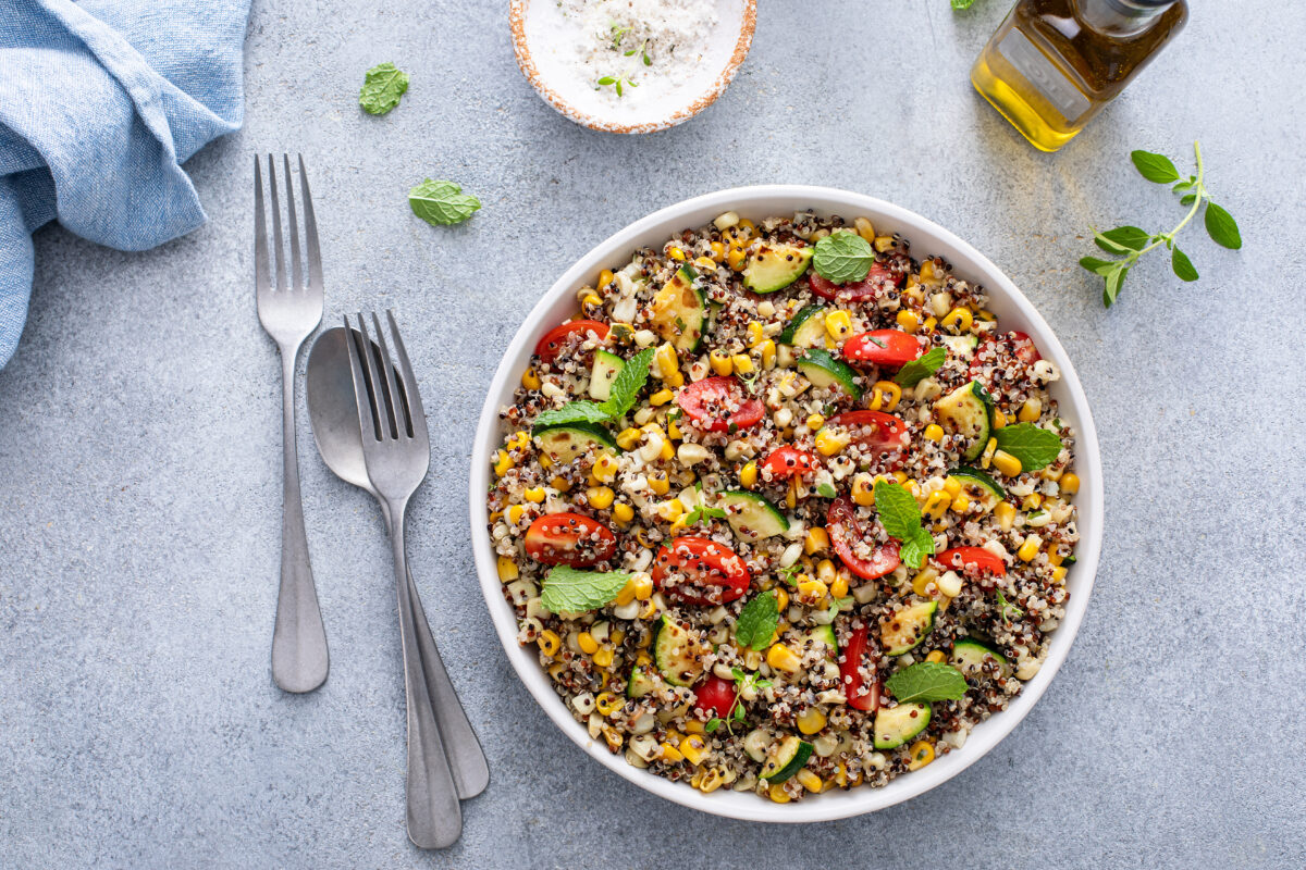 Warm quinoa salad with tomatoes, corn and zucchini with fresh mint and herbs, overhead shot