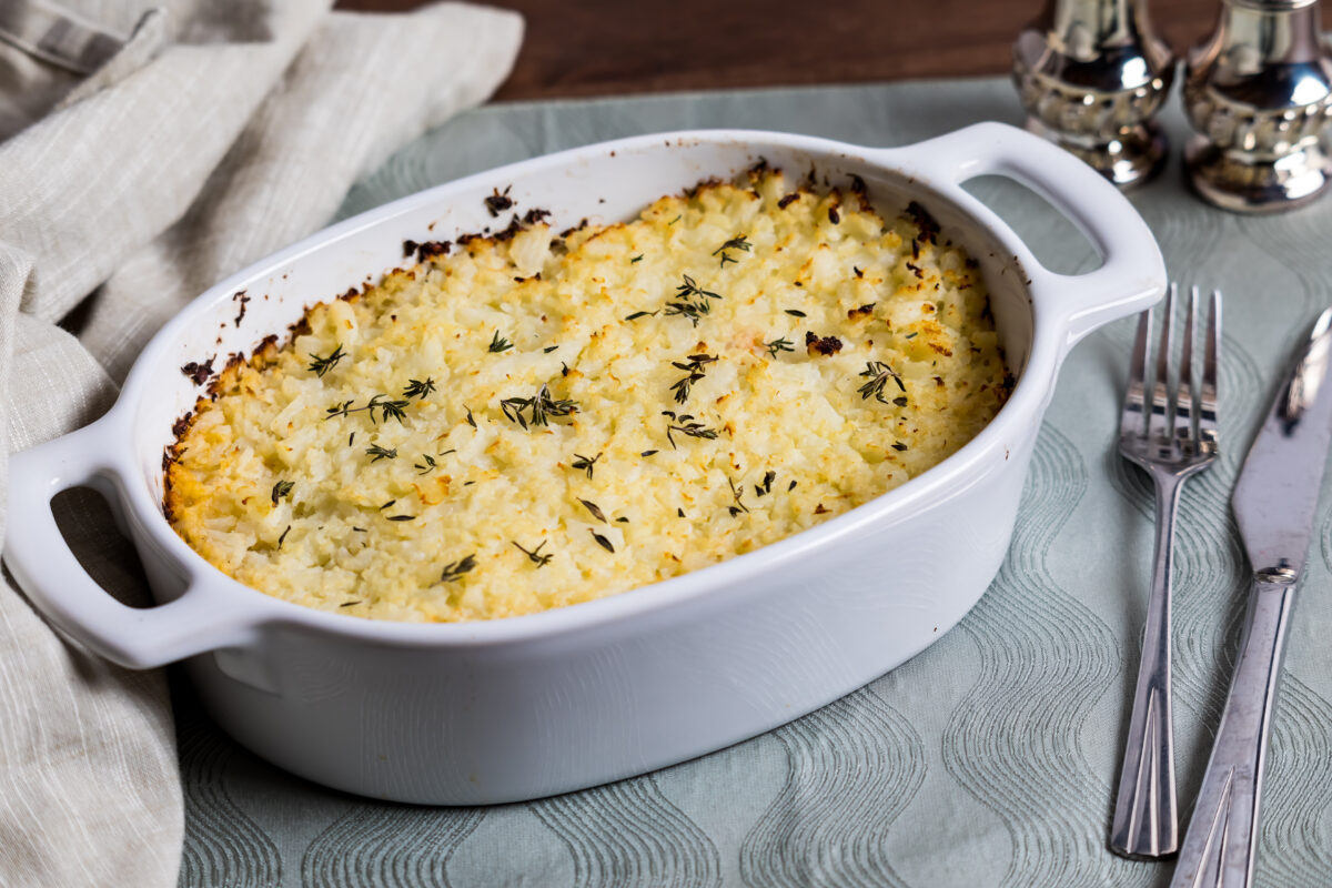 A casserole dish of homemade shepherd's pie topped with mashed cauliflower, hot out of the oven.