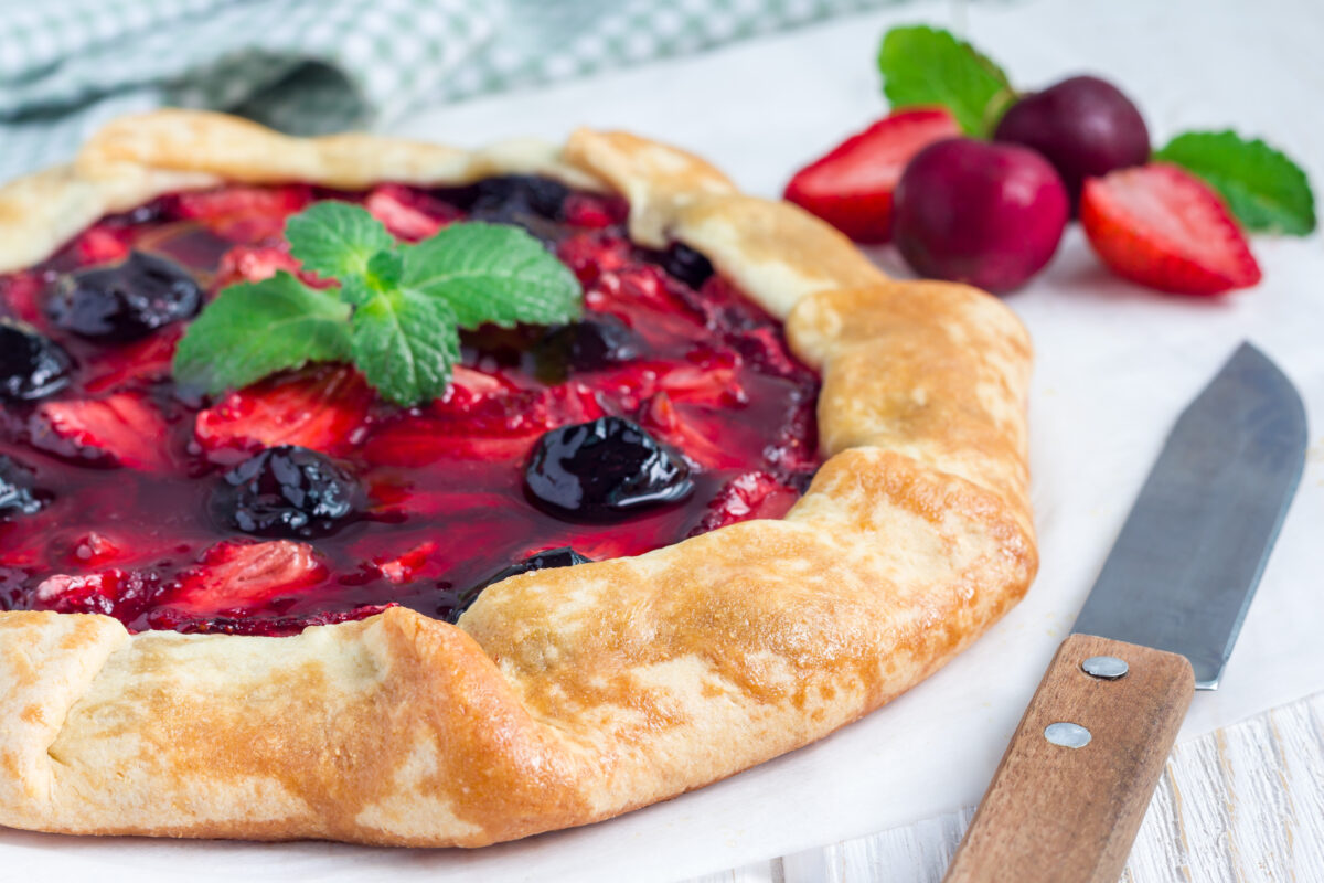 strawberry cherry galette garnished with fresh mint on a cutting board