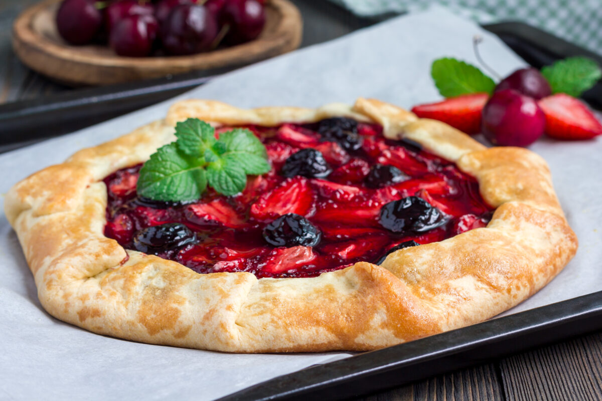 strawberry cherry galette on a baking sheet garnished with fresh mint