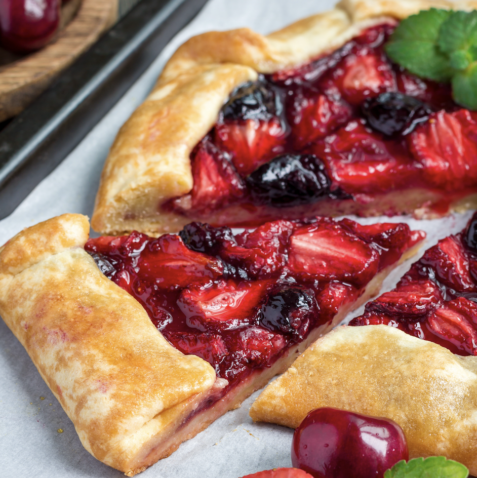 strawberry cherry galette garnished with fresh mint cut into slices on a baking sheet