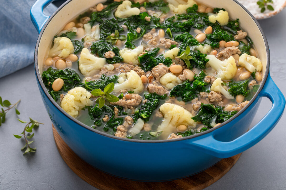 tuscan white bean soup with turkey sausage in a blue pot ready to serve