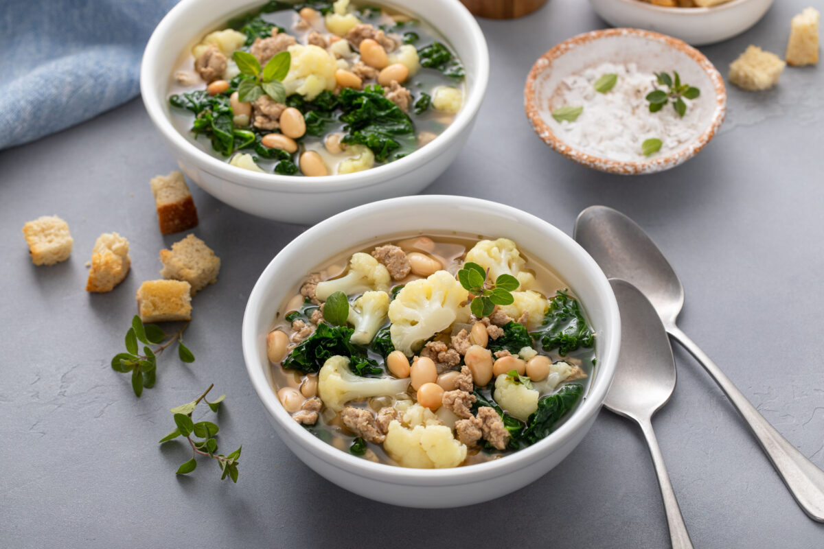 tuscan white bean soup with cauliflower and turkey sausage in two serving bowls