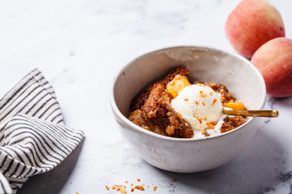 Portion of peach cobbler with a scoop of ice cream in a bow