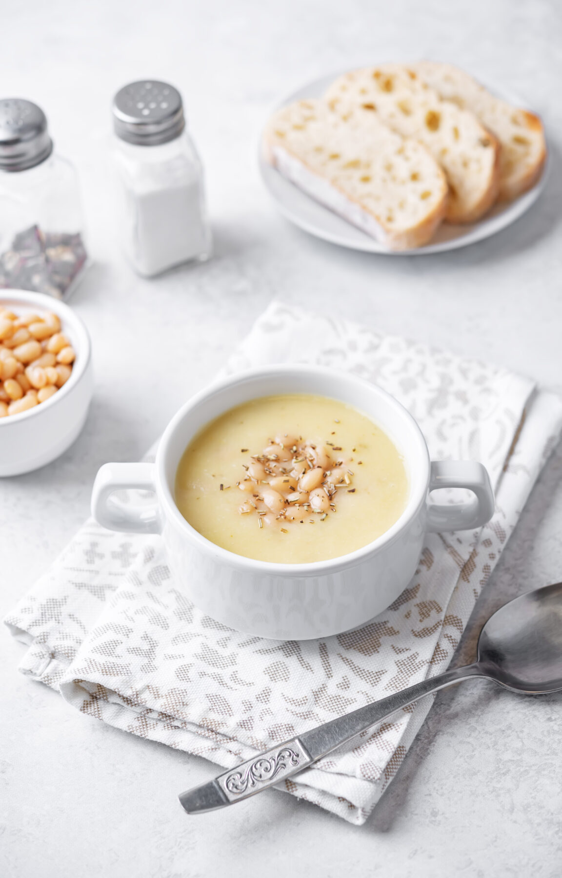 creamy white bean soup in a serving bowl with a spoon