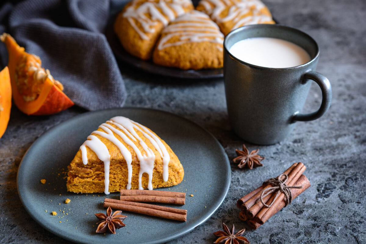 pumpkin scones with maple glaze on a serving plate with cinnamon sticks and star anise