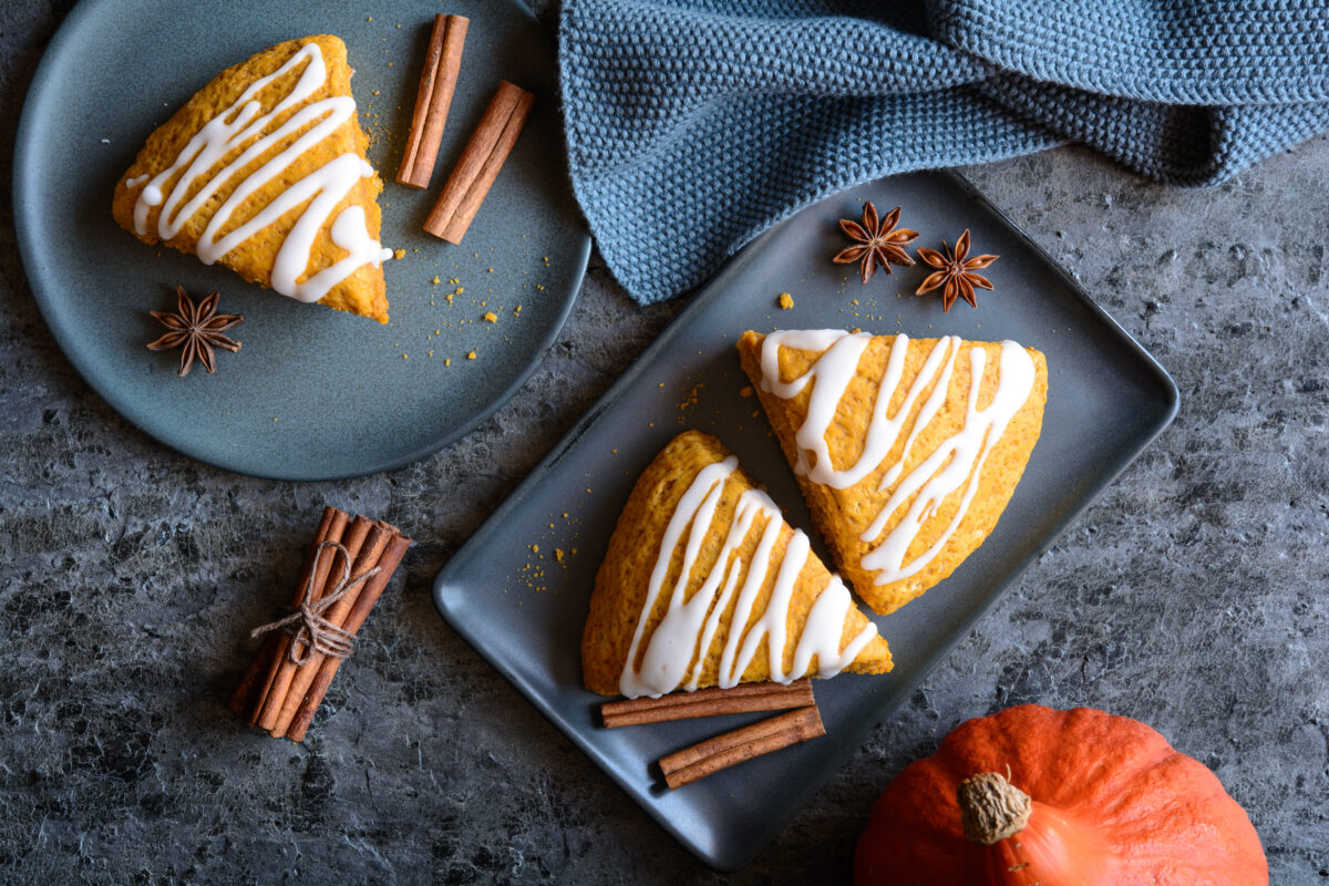 pumpkin scones with maple glaze on a dark serving plate 